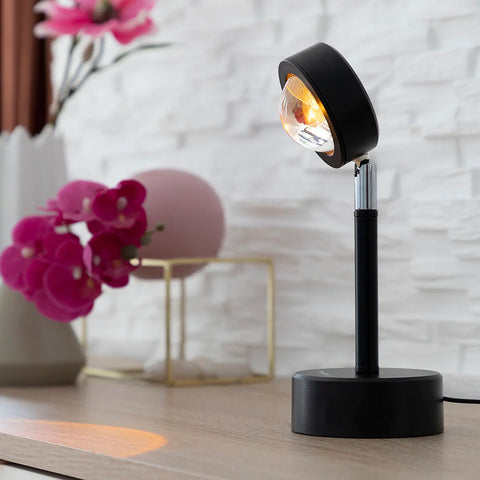 Lampada proiettore tramonto su tavolo con fiori rosa in ambiente moderno, illuminazione speciale per decorazione e atmosfera accogliente